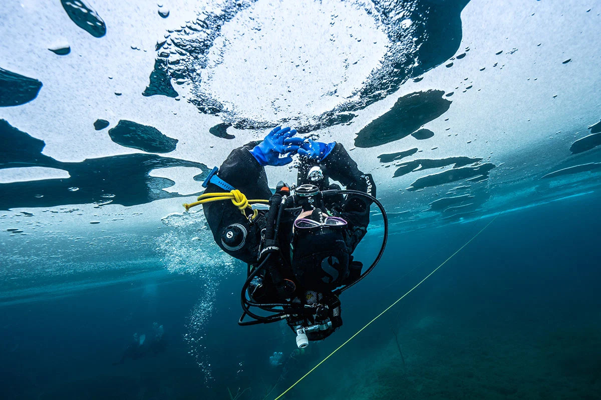 An ice diver beneath the opening in a frozen surface.