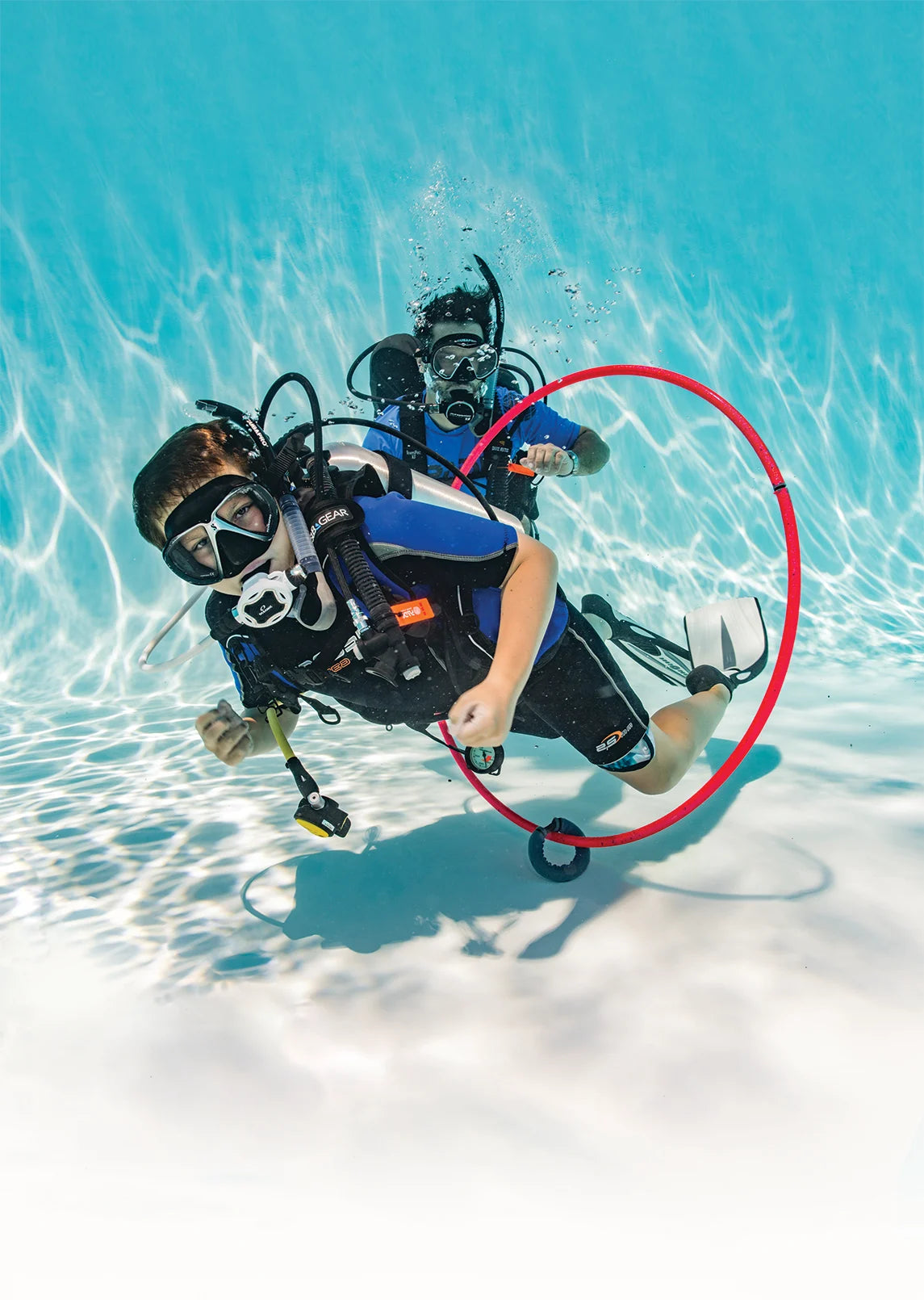 A young diver practices scuba skills in a pool.