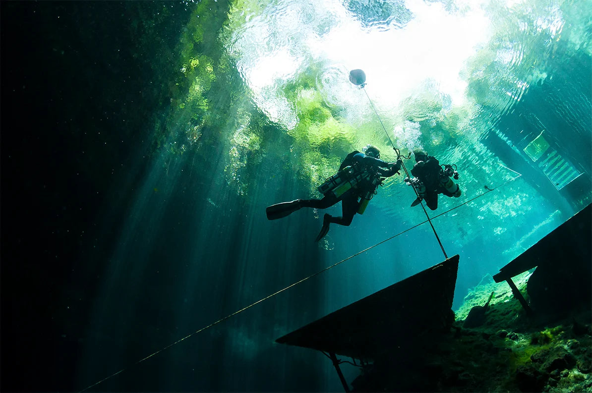 Technical divers descend beside a submerged structure.