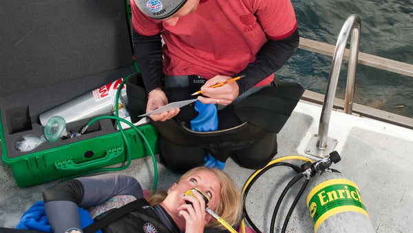 An emergency-oxygen training scenario beside a boat ladder. © PADI 2026