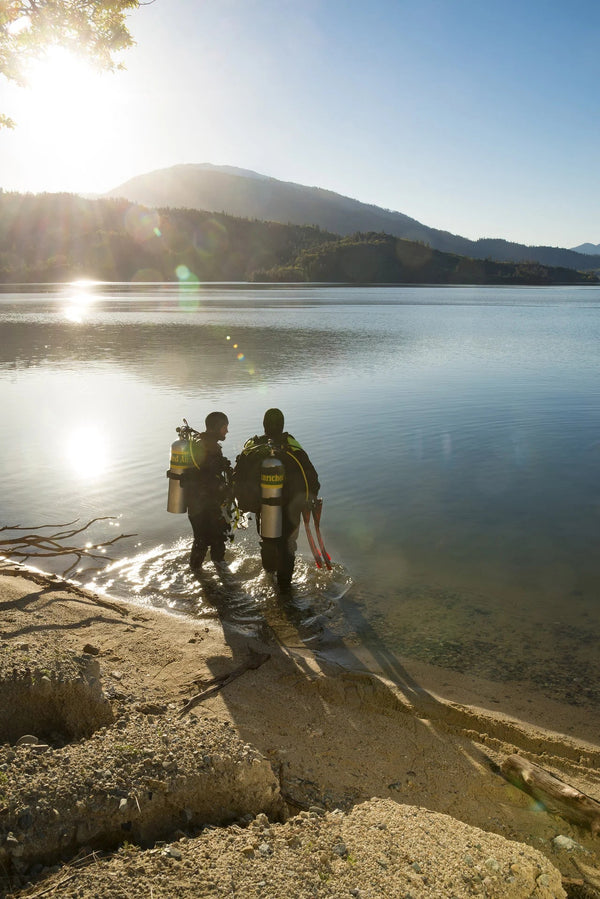 Cold-water divers carry enriched-air cylinders toward a lake. © PADI 2016